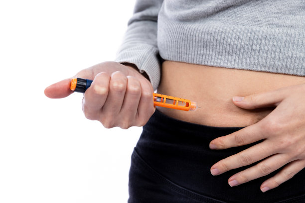 一名年轻女子正在往肚子里注射胰岛素图片下载