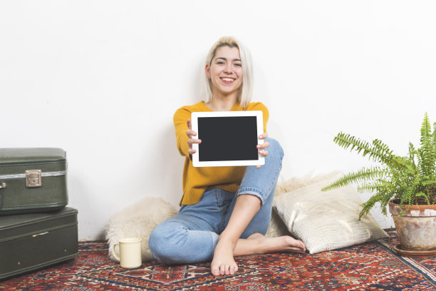 快乐迷人的年轻女子显示一个空白的白色笔记本电脑屏幕的相机为您的copyspace和文本图片下载