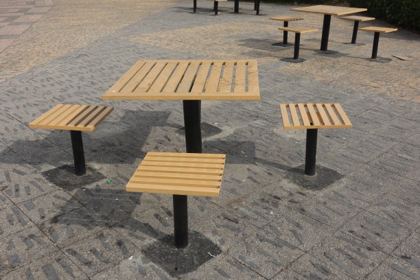 公园里的一个木凳和一个桌子在秋天的季节-木制复古长椅和一个小桌子在公共公园-装饰华丽的金属腿和扶手图片下载