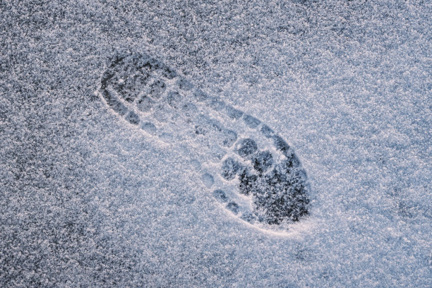 靴子在雪地里留下脚印，鞋子适合冬天在寒冷的天气和冰天雪地里行走图片下载
