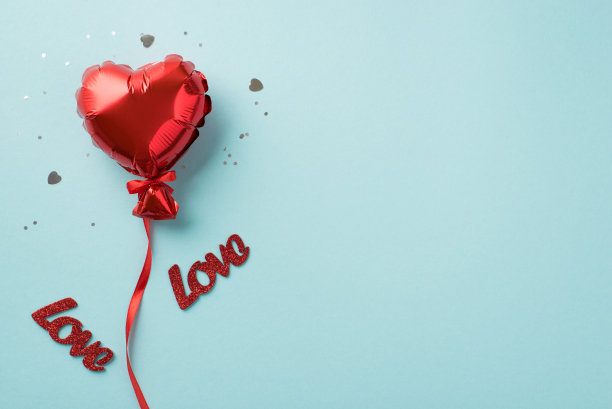 俯视图照片的情人节装饰红色心形气球与丝带亮片彩纸和题词爱在孤立的柔和的蓝色背景与copyspace图片下载