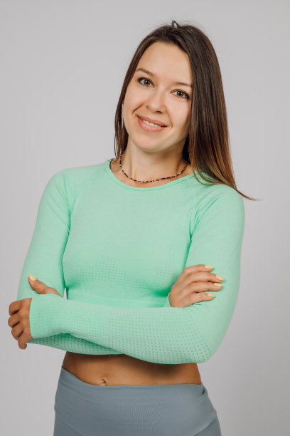 美丽的黑发摆姿势。这是一张快乐的年轻女子的照片，她穿着瑜伽服或健身服，在灰色孤立的背景下在工作室里摆姿势。她交叉着双臂，歪着头图片下载