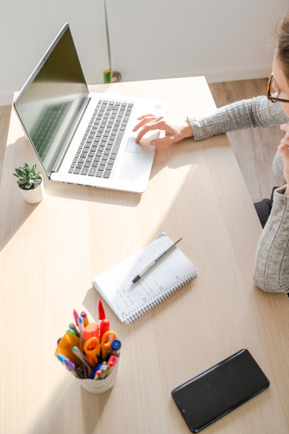 在西班牙马略卡岛帕尔马的办公室里，一个白人女孩在她的桌子上用笔记本电脑工作。图片下载