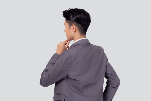 背部穿着西装的年轻亚洲商人站在白色的背景上，为成功而思考的想法孤立起来，背面是英俊商人的肖像，富有创意和想象，问题和计划决定。图片下载