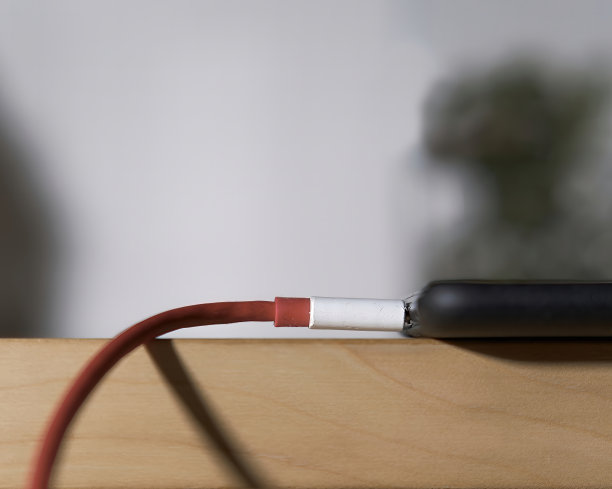 一张在木桌上插入充电器的智能手机的特写照片图片下载