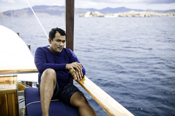 坐船旅行时坐在甲板上的亚洲人图片下载