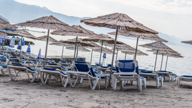 晒着太阳的躺椅撑着伞站在泳池边的一张围栏照片后面图片下载