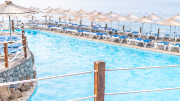 带阳伞的太阳躺椅排列在泳池库存照片图片下载