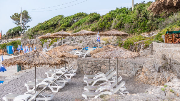 鹅卵石海滩与太阳躺椅和阳伞库存照片图片下载