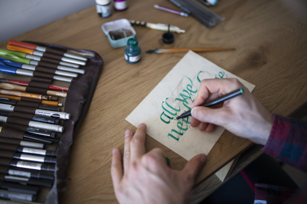 年轻人用绿墨水在纸上练习书法图片下载