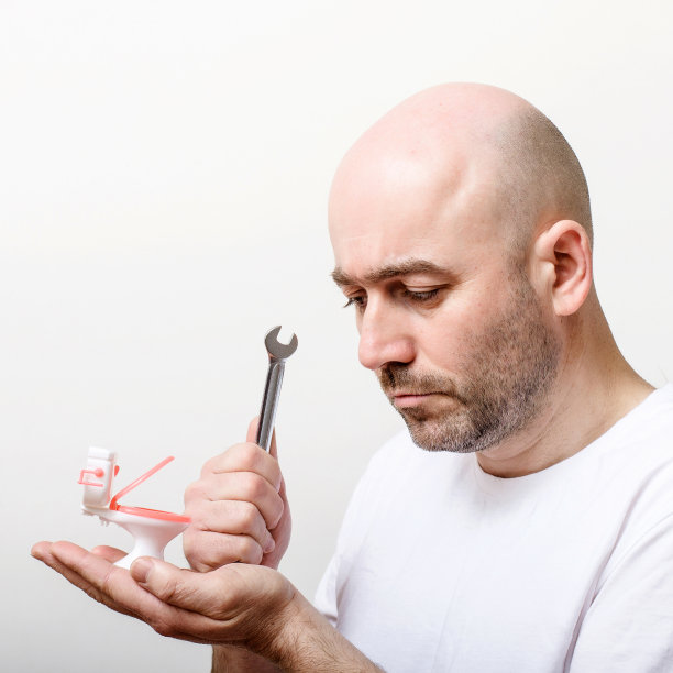 一个拿着玩具马桶和扳手的秃顶男人图片下载
