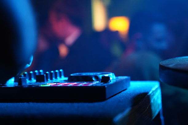 在一个俱乐部的派对上，无法辨认的男性DJ在转盘上播放音乐的特写。图片下载