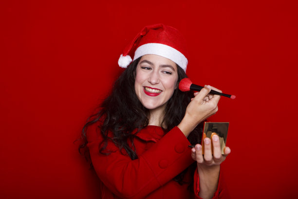 戴着圣诞帽的快乐女人用红刷子化妆图片下载