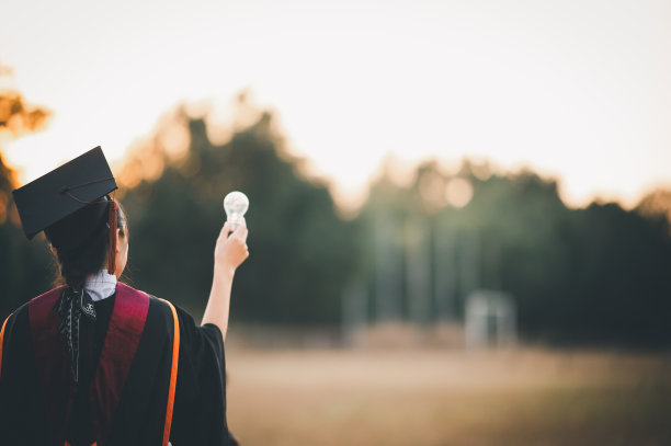 毕业生戴着黑帽子拿着大学毕业证书，向概念教育祝贺。毕业典礼，祝贺大学毕业生。图片下载