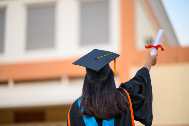 毕业生戴着黑帽子拿着大学毕业证书，向概念教育祝贺。毕业典礼，祝贺大学毕业生。图片下载