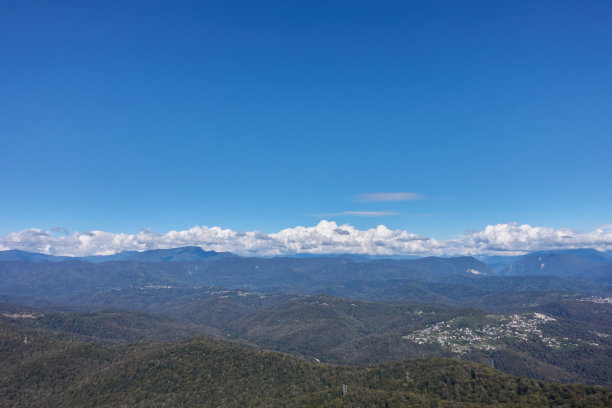 鸟瞰一个山村，白色的积云，森林和山脉。图片下载