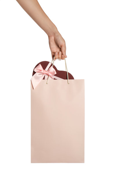 白色背景下，女人拿着装满礼品盒的购物袋，特写镜头图片下载
