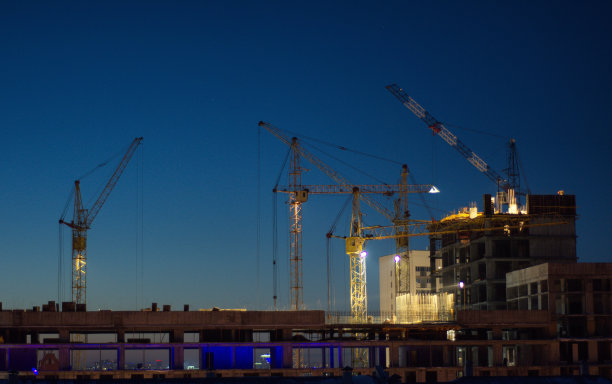 起重机在日落和黑暗的天空的背景下建造了一座房子图片下载