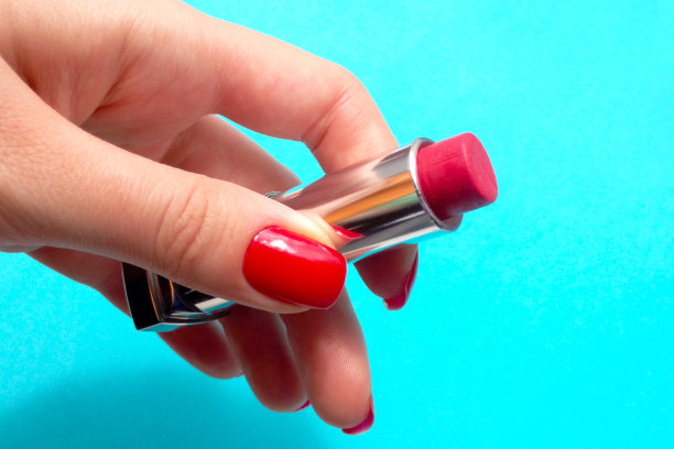 一个女孩手上的口红在蓝色背景上的特写镜头图片下载