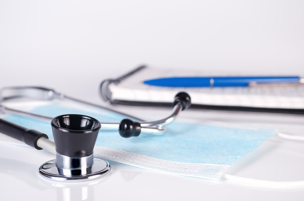 听诊器，医用口罩，记事本和蓝色铅笔在白色背景上接近图片下载