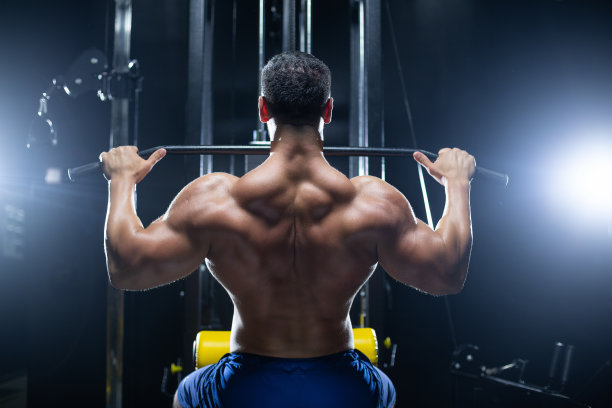 英俊的健身男子正在进行背部锻炼，使用推力上块机在健身房，后视图图片下载