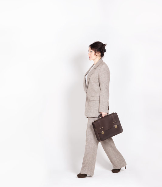 一个穿着长裤套装，带着公文包和智能手机的精明的年轻女人图片下载