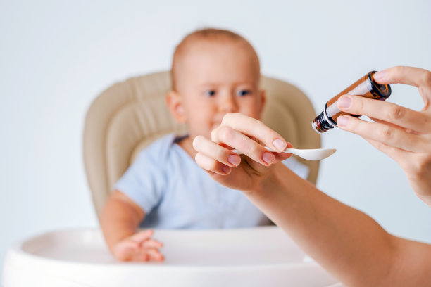 母亲的手把新生儿的药倒进勺子里。有选择性的重点图片下载