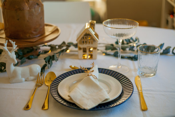 时尚的圣诞餐桌，金色的餐具。节日的盛宴。新年桌上的装饰品。图片下载