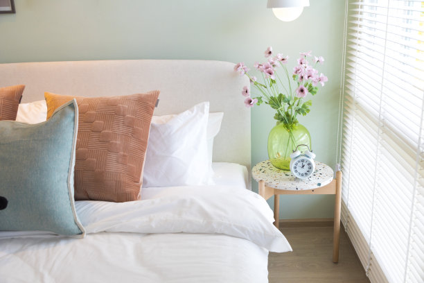 卧室的桌子上有一个绿色的玻璃花瓶，上面插着一束漂亮的花。图片下载