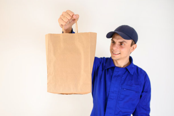 年轻的快递员正在送一个生态纸袋包裹。图片下载