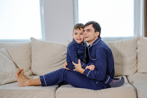 快乐的年轻父亲躺在床上和他的儿子玩图片下载