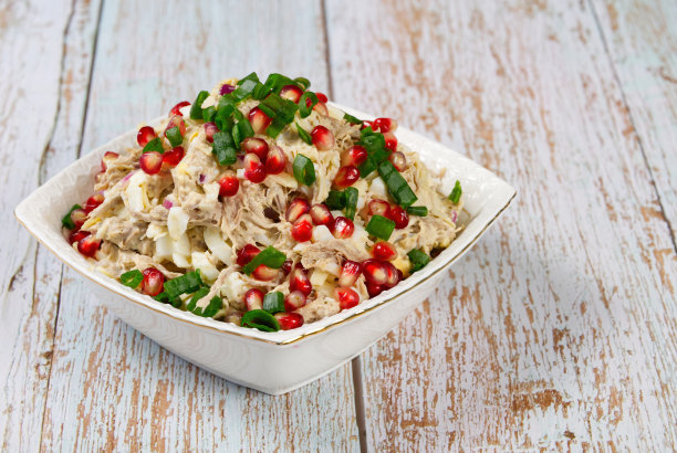 新鲜的沙拉，肉，蔬菜和石榴在一个白色的盘子在木桌上图片下载