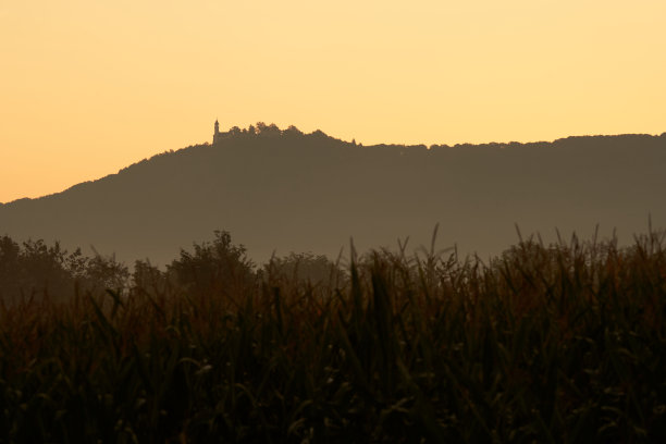 柔和的彩色风景拍摄于秋天的日出。农田前有一座带城堡的山。德国,泰克。图片下载