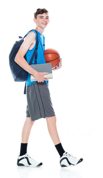 白人男大学生背着背包走在白色背景的前面，手里拿着书和运动球图片下载