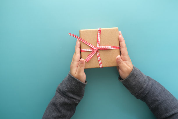 孩子手拿自制的礼盒在浅绿色的背景上图片下载