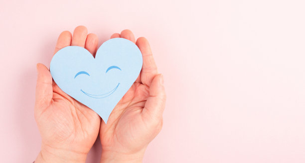 捧着一颗心，贴着笑脸，彩色背景贴着复印空间，情人节贺卡图片下载