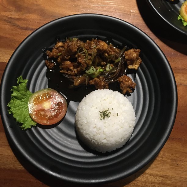 黑色陶瓷盘子上的黑胡椒鸡肉米饭和番茄图片下载