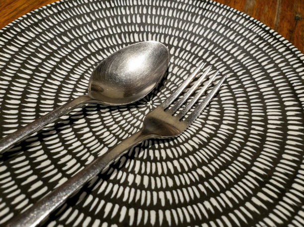 金属勺子和叉子放在装饰华丽的陶瓷盘子上图片下载