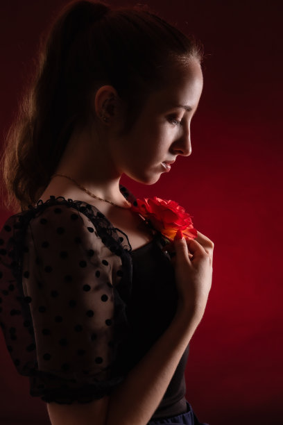 一个年轻美丽的女孩的肖像与花在红色背景的背光图片下载