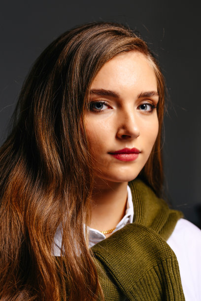 一个漂亮的年轻女孩，脖子上围着一件绿色的毛衣。图片下载