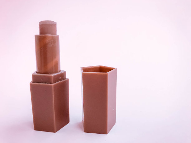 哑光唇膏在一个粉红色明亮的哑光背景。浅褐色的心型口红，柔和的棕色阴影。裸唇妆，化妆袋小巧管图片下载