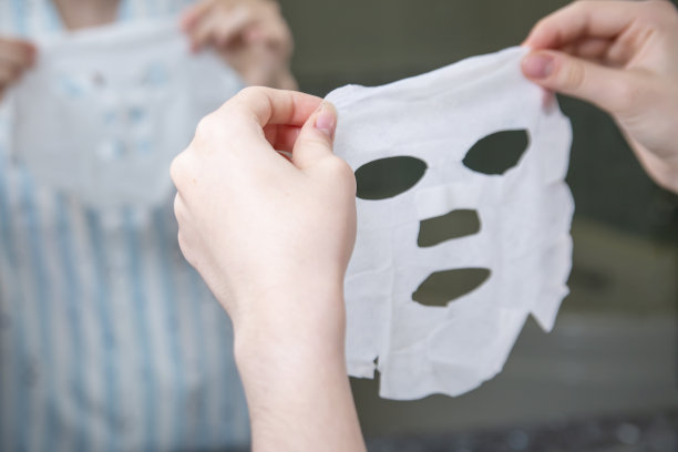 女孩在家里打开了一个用于皮肤护理的织物化妆面膜。美容,生活方式。图片下载