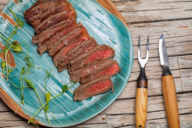 多汁的半熟牛排片与香草香料和盐陶瓷板。图片下载