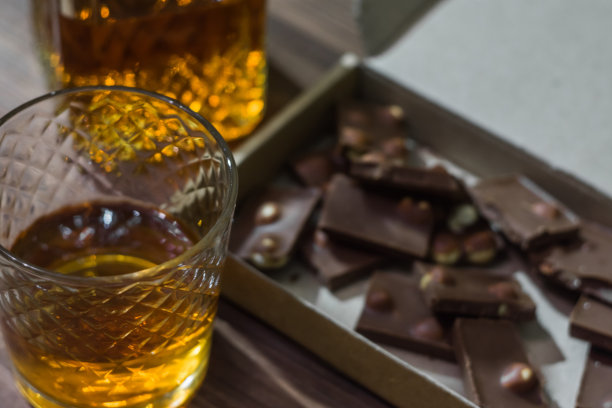 一个玻璃碎片和一个装有威士忌和巧克力的瓶子的特写照片图片下载