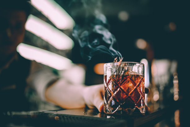 男人手拿酒保在酒吧抽着烟调制鸡尾酒图片下载