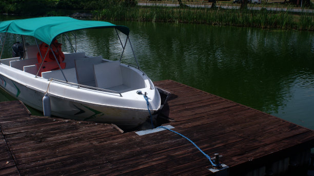 一艘机动游船停泊在一个房地产公园的人工河码头上。图片下载