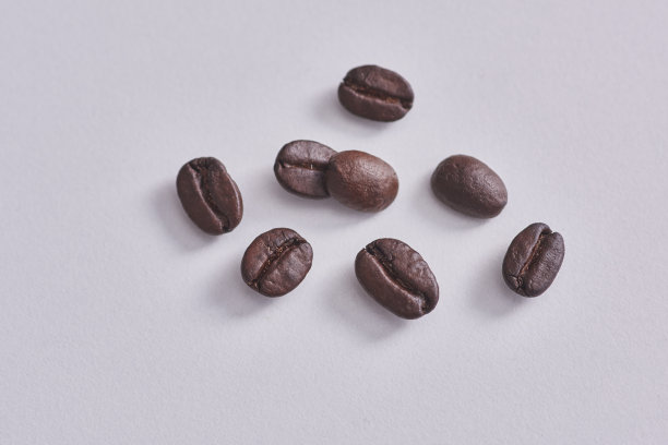 用木勺和咖啡豆拉近，咖啡豆白色的背景和孤立。图片下载