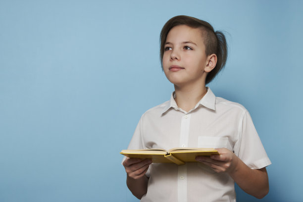 学校男孩的肖像，蓝色背景的书图片下载