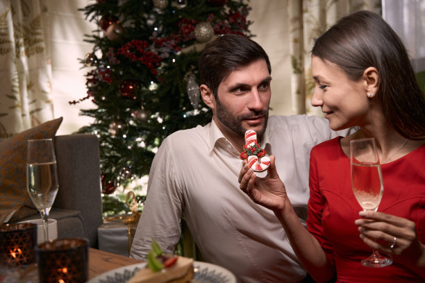 快乐的年轻女士拿着饼干在平安夜招待她的男朋友图片下载