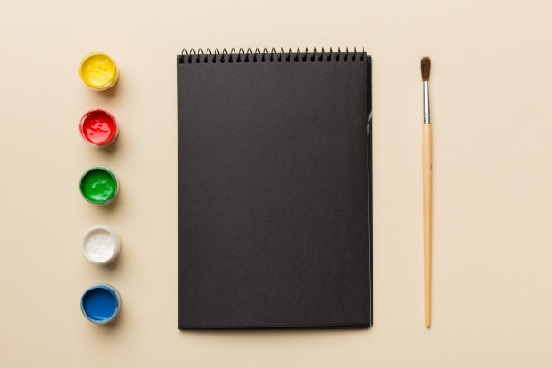 相册页和油漆，铅笔，画笔上的彩色背景。顶部视图与空的空间。工作场所的创造力。家庭教学概念图图片下载